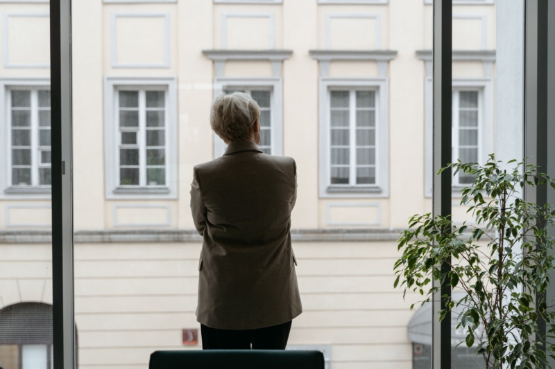 Person blickt von hinten durch eine Glastür nach draußen, Sinnbild für die moralische Frage im Verteidigungsmarkt